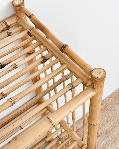 Close-up of a bamboo shelf against a white wall.