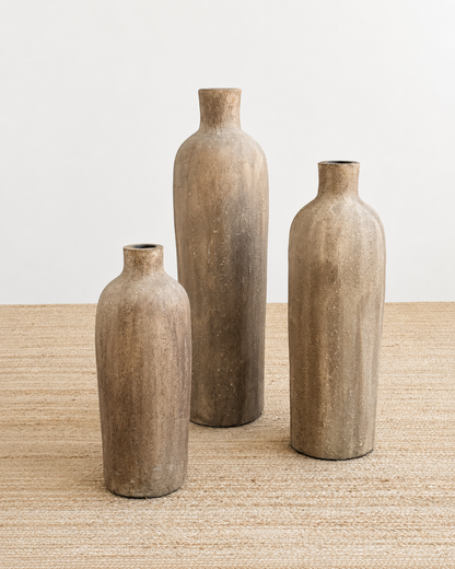 Three rustic-style vases of different sizes on a textured surface with a neutral background