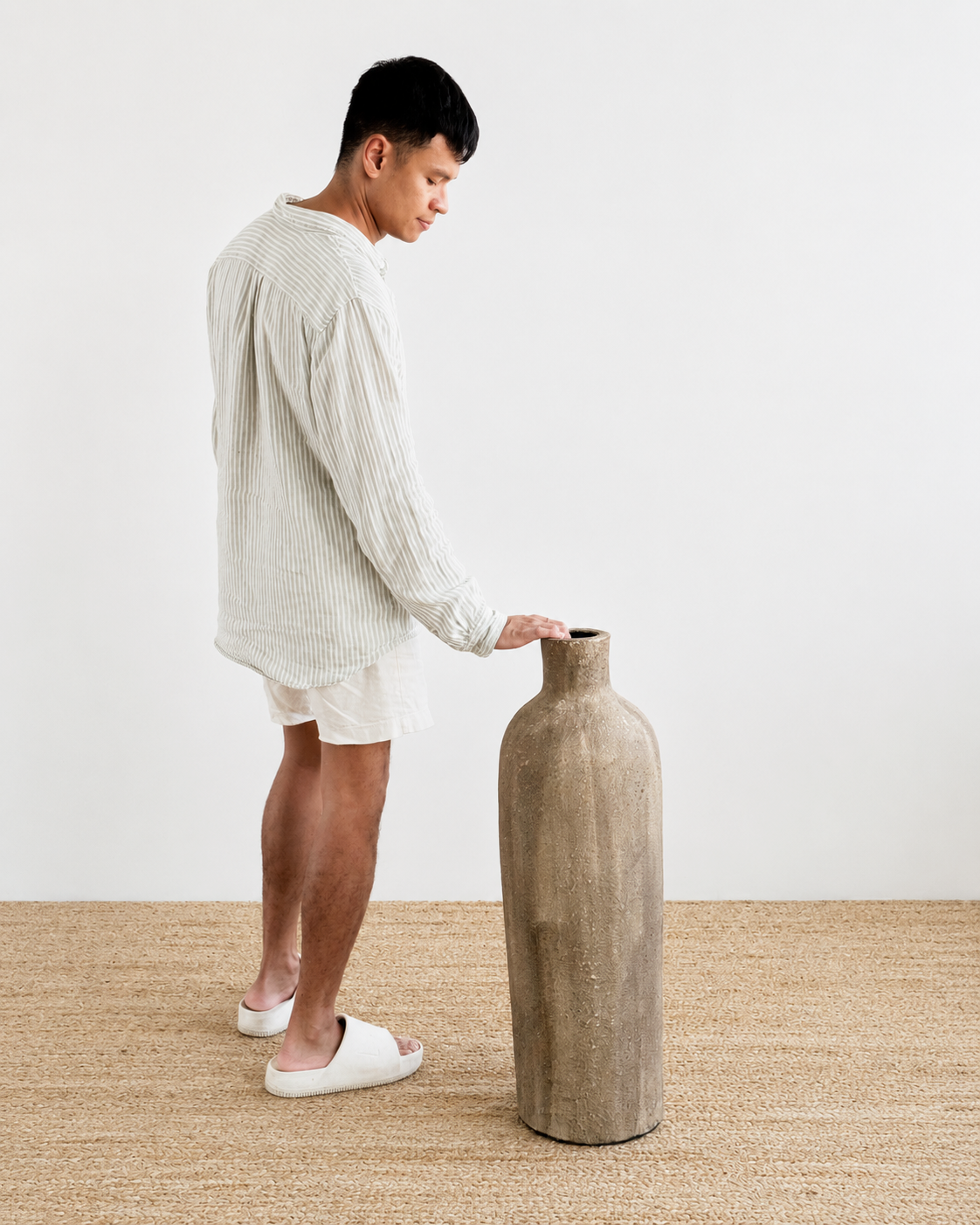 Man holding a textured vase on a neutral background