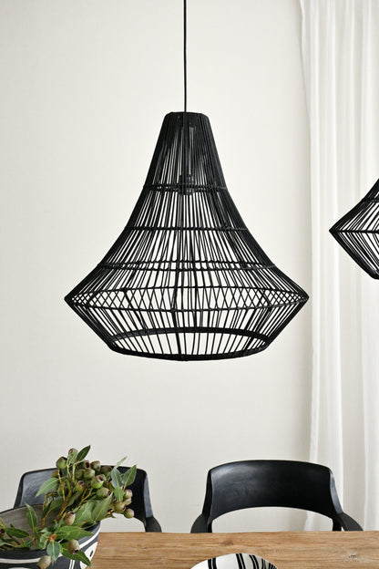 Black woven pendant light fixture hanging above a dining table with chairs.