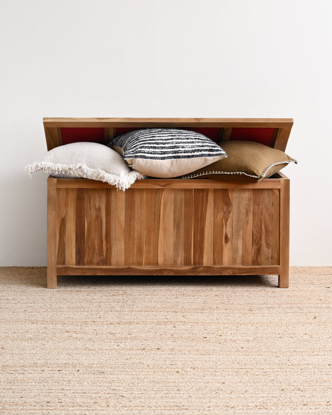Wooden storage bench with pillows on a neutral background