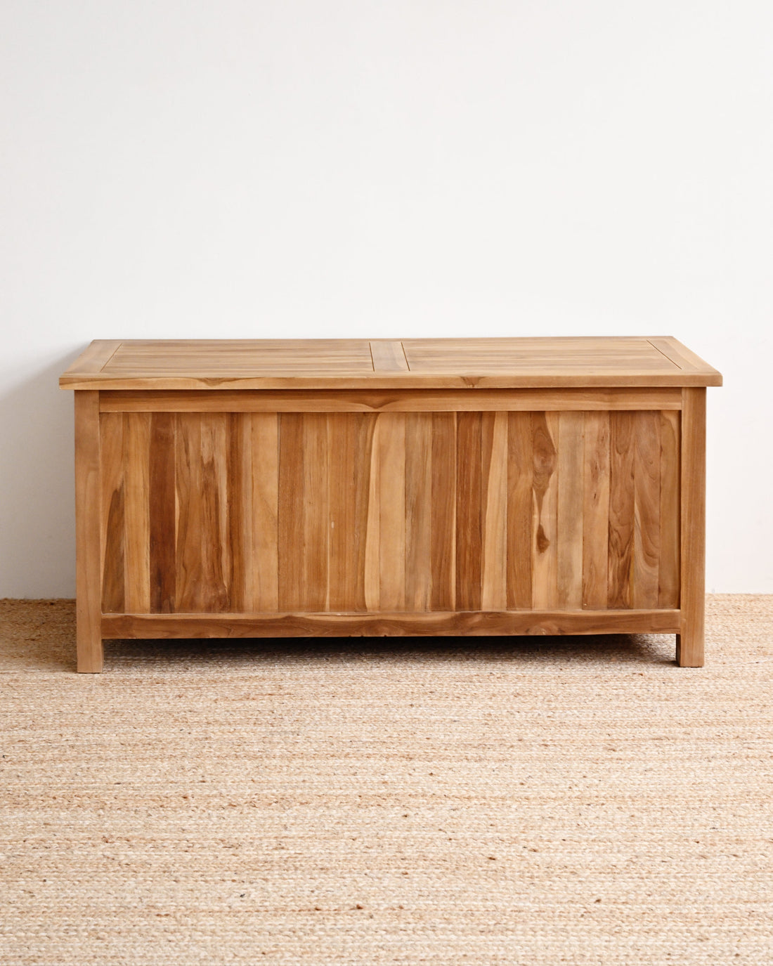 Wooden storage chest on a beige carpet with a white wall background
