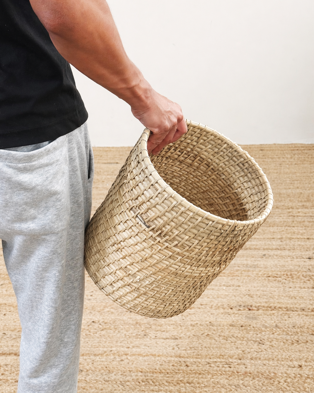 Person holding a woven basket on a wooden floor