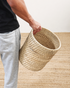 Person holding a woven basket on a wooden floor