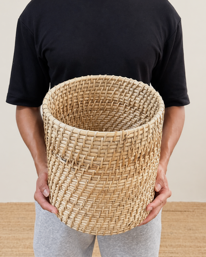 Person holding a woven basket against a neutral background