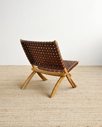 Woven chair with wooden frame on a beige carpet against a white wall