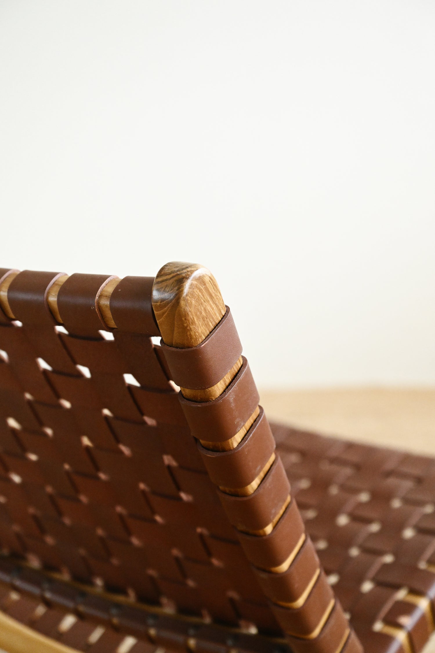 Close-up of a woven brown chair with a wooden armrest on a blurred background