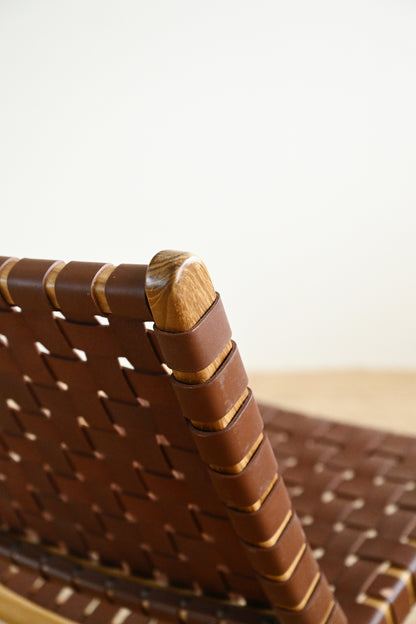 Close-up of a woven brown chair with a wooden armrest on a blurred background