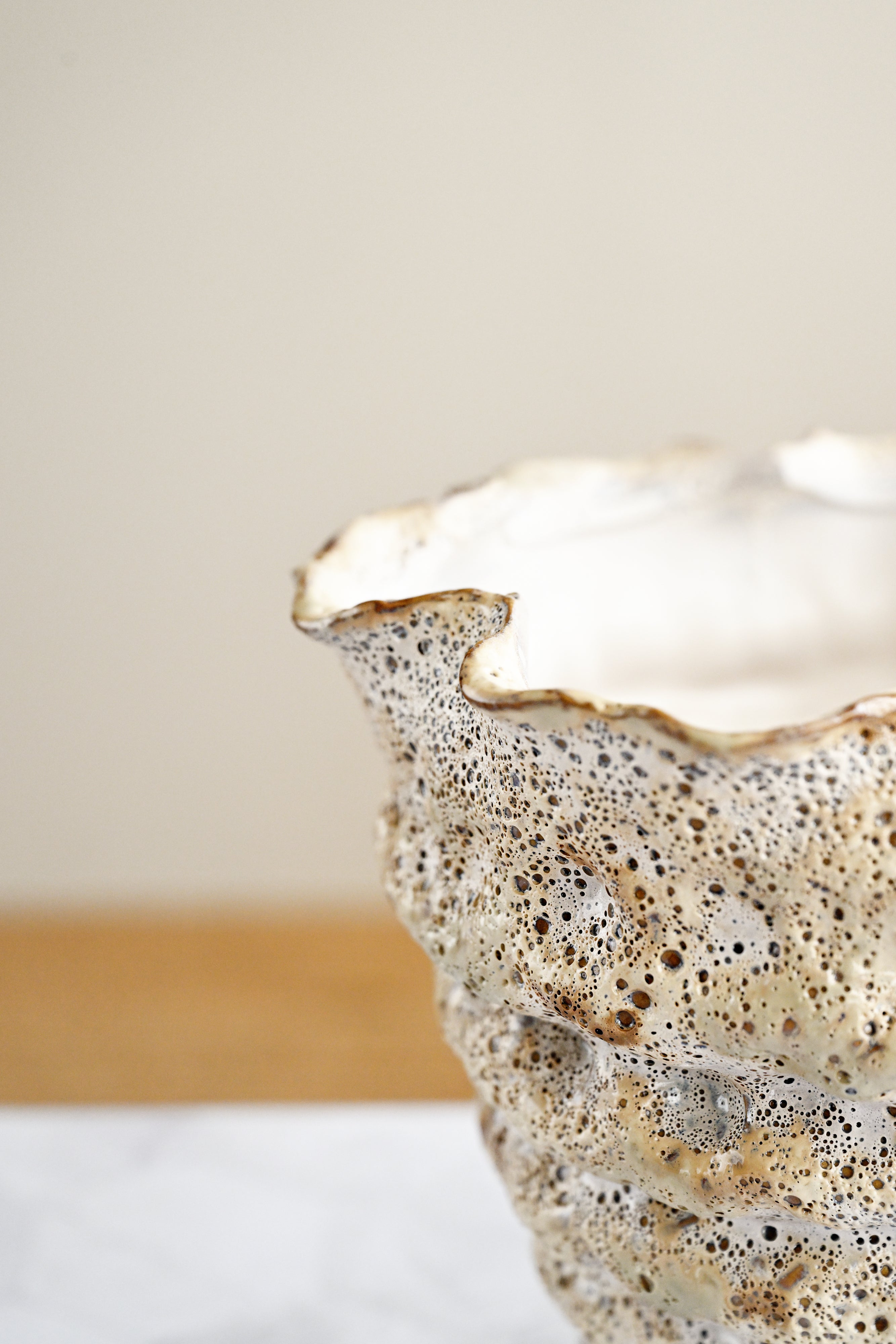 Close-up of a ceramic bowl with textured surface and gold rim on a neutral background