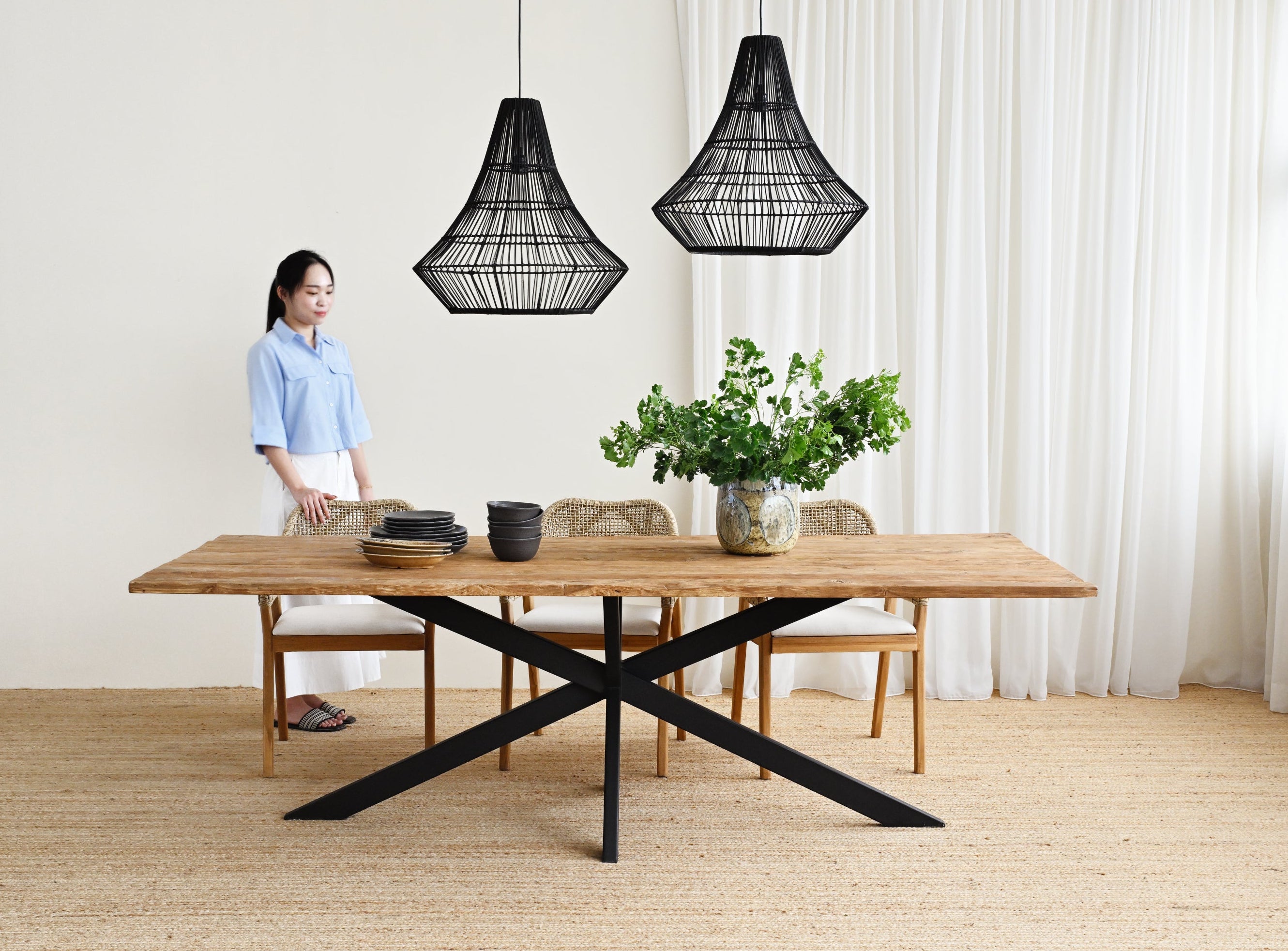 Person standing in a modern room with a wooden table and decorative lamps.