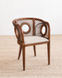 Wooden chair with a woven backrest and cushion on a textured surface