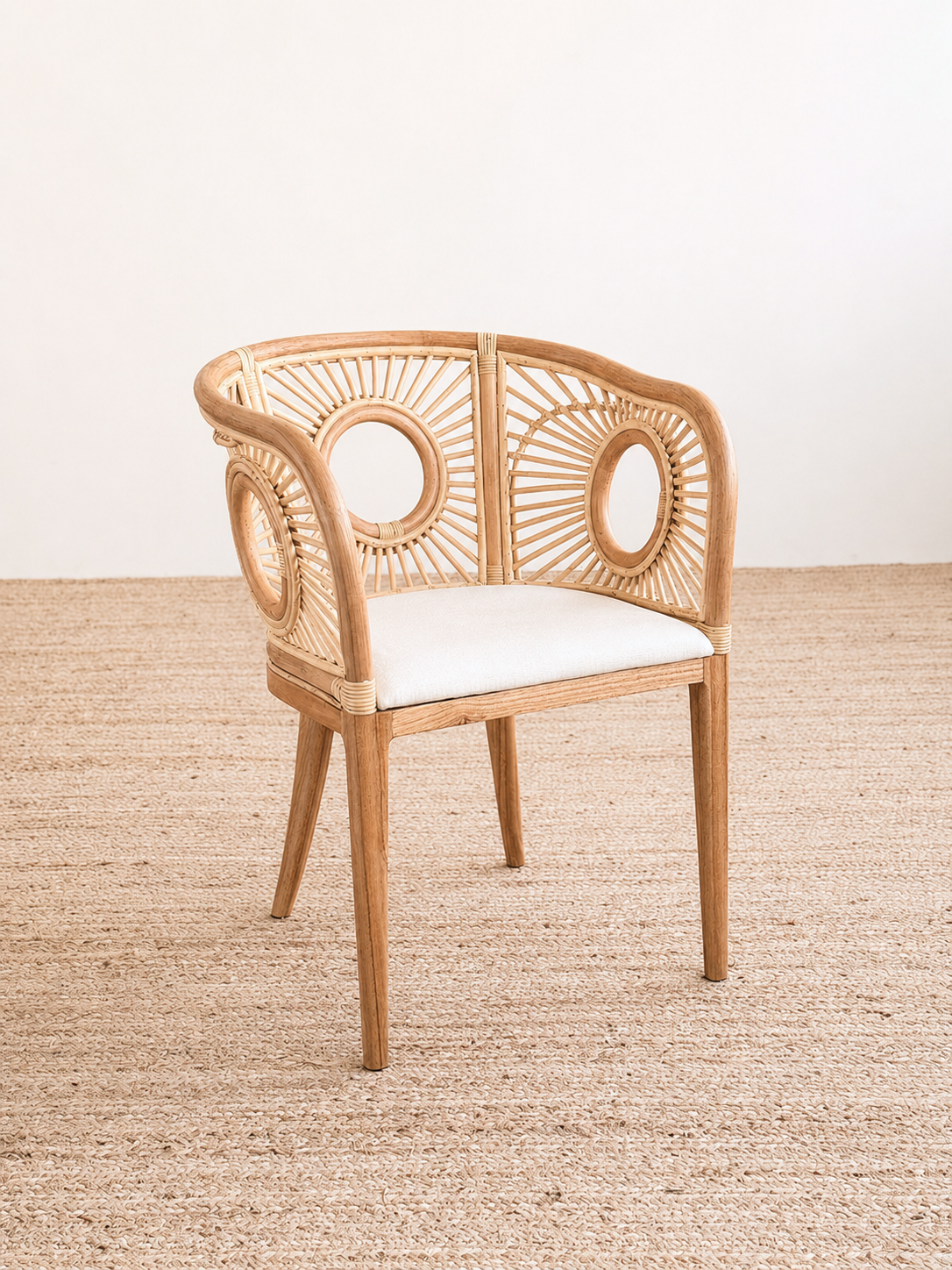 Wicker chair with a white cushion on a textured beige floor.