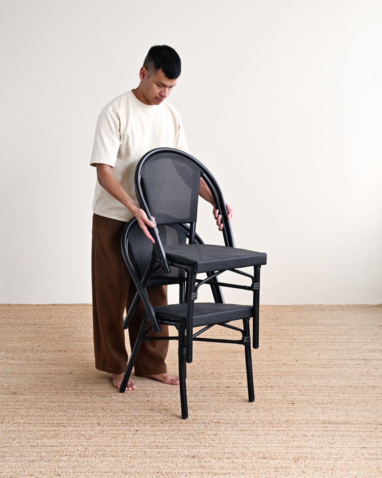 Person assembling a black chair in a minimalistic setting