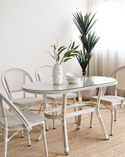 White dining set with table and chairs in a room with plants and curtains.