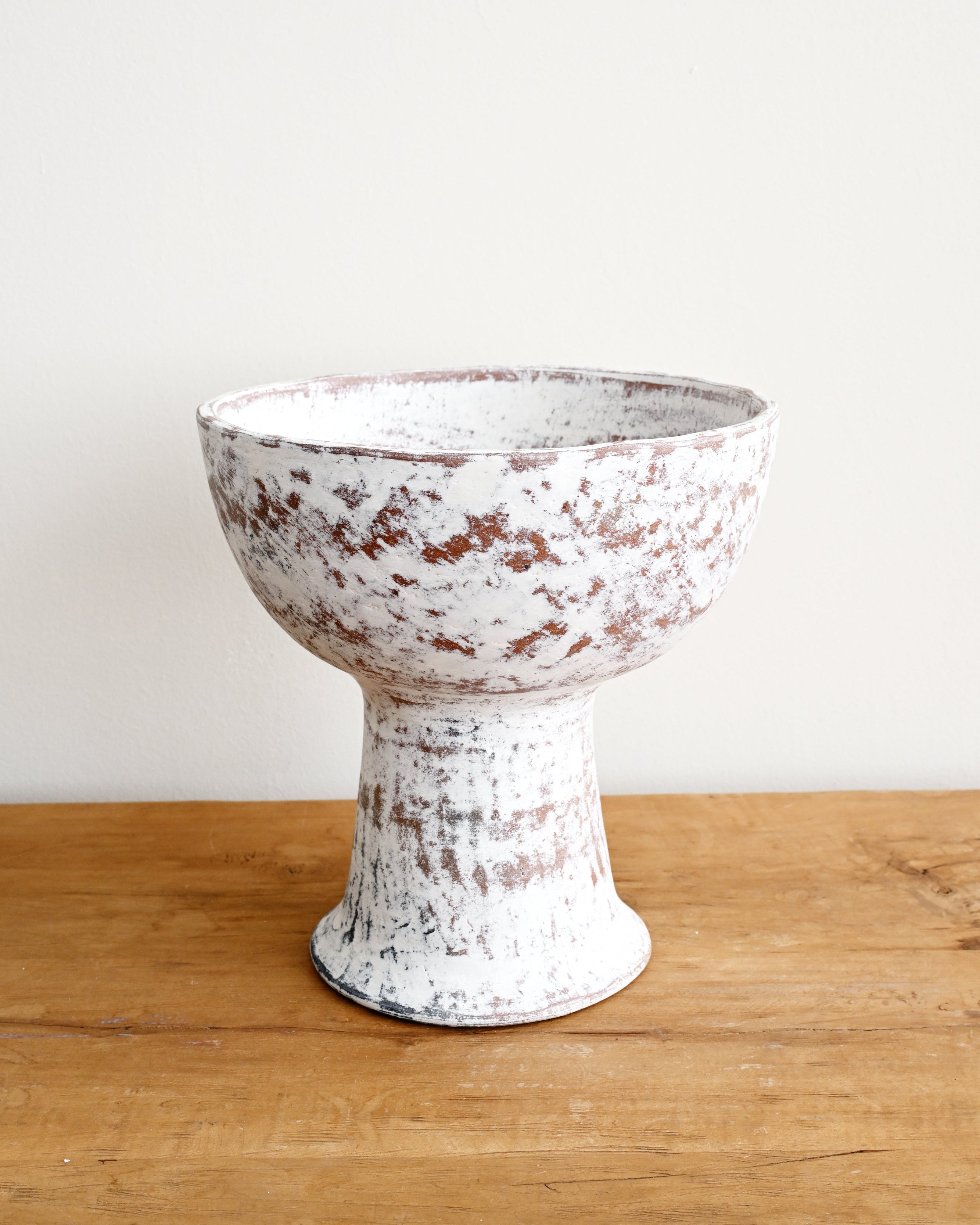 White distressed ceramic bowl on a wooden surface with a white background