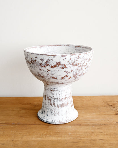 White distressed ceramic bowl on a wooden surface with a white background
