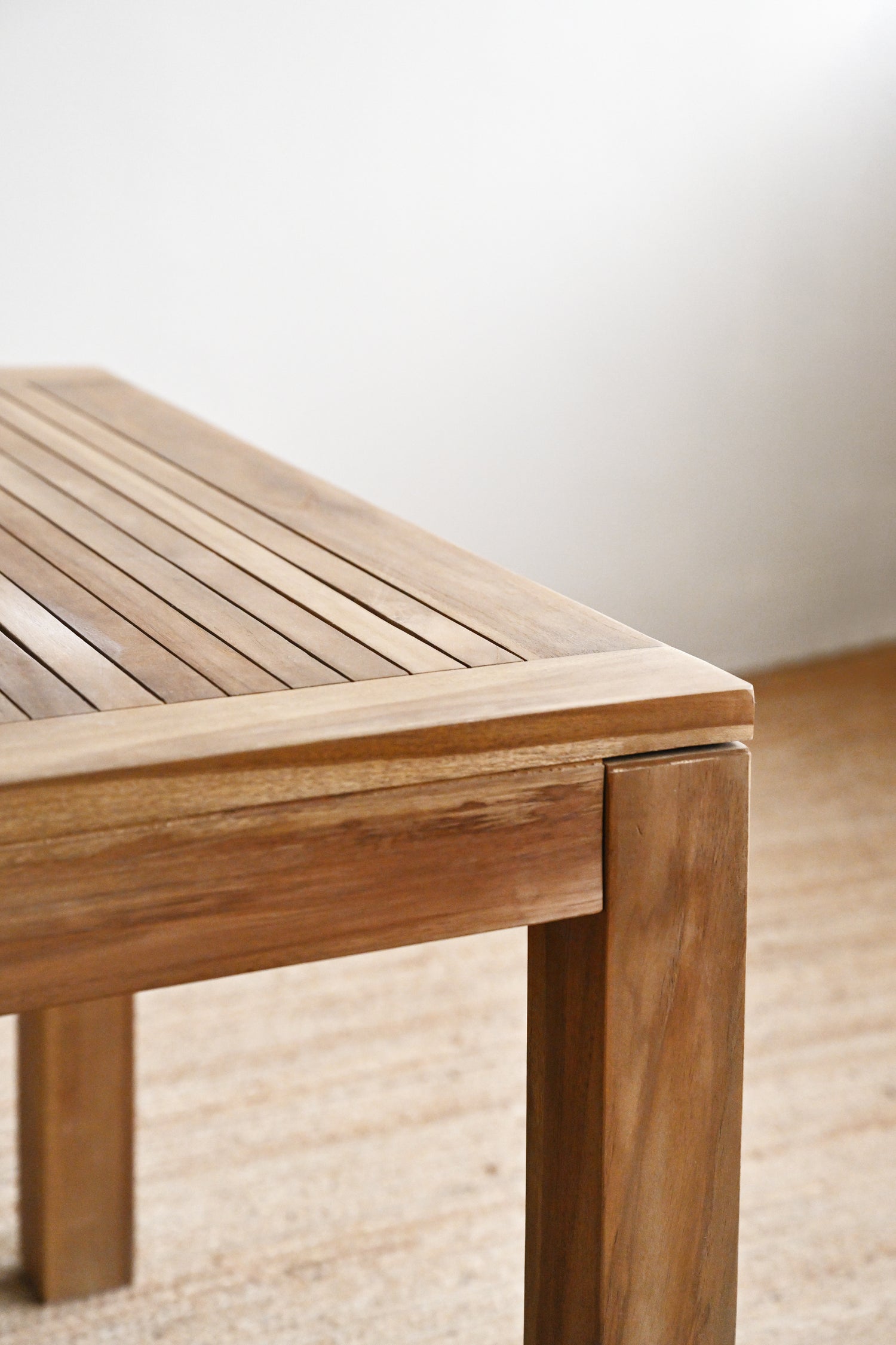 Wooden bench with a slatted design on a light wooden floor.