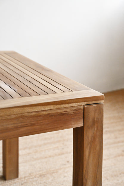 Wooden bench with a slatted design on a light wooden floor.