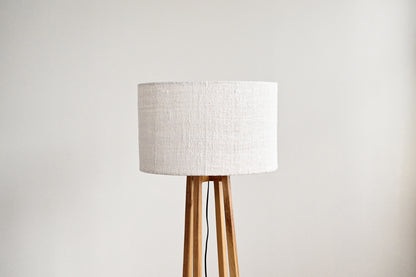 Floor lamp with a white lampshade and wooden base on a light gray background
