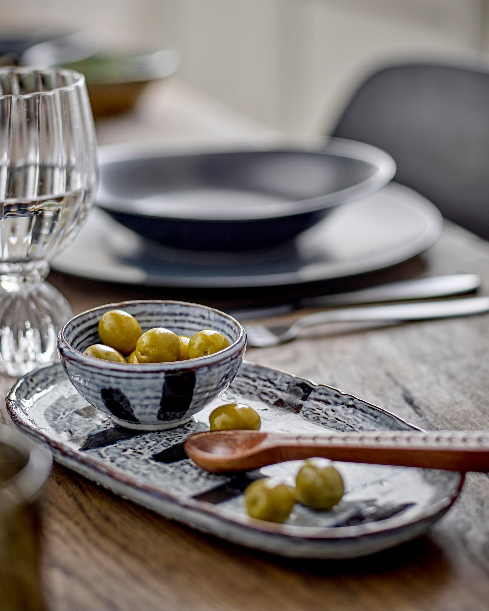 Dining table setting with ceramic bowls, plate, and small bowl on a wooden surface.