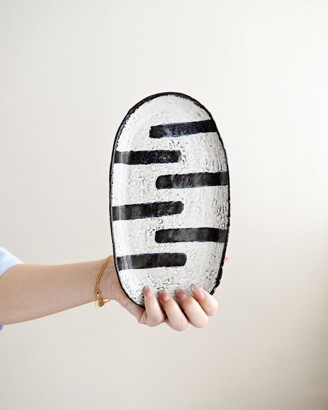 Person holding a black and white striped oval object against a plain background