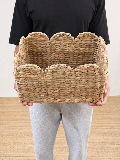 Person holding a woven basket against a neutral background