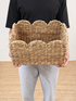 Person holding a woven basket against a neutral background
