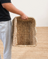 Person holding a woven basket on a wooden floor.