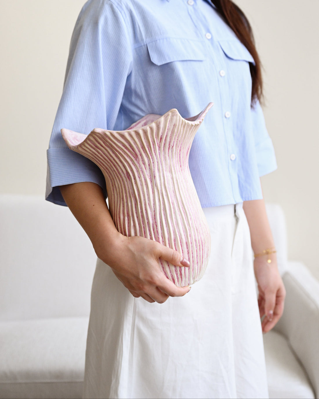 Person holding a pink textured vase against a neutral background