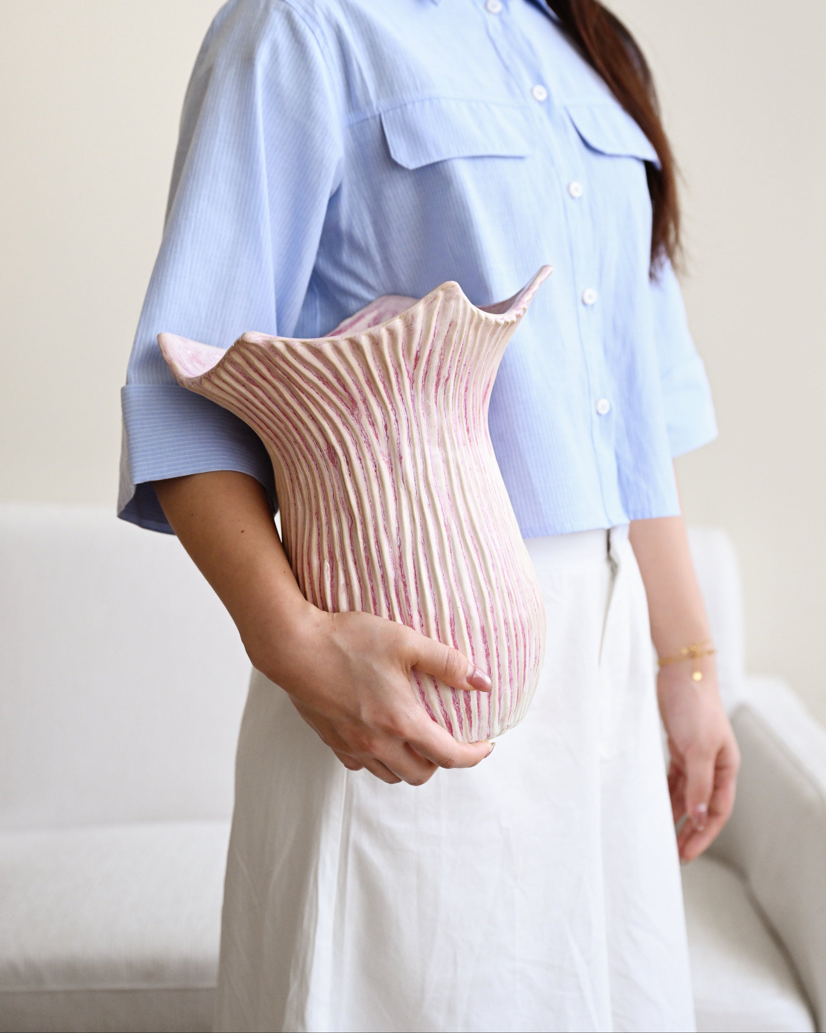 Person holding a pink textured vase against a neutral background