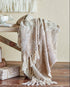 A beige and brown plaid Gabriela Throw by Bloomingville draped over the edge of a wooden table, with a cozy, festive atmosphere.