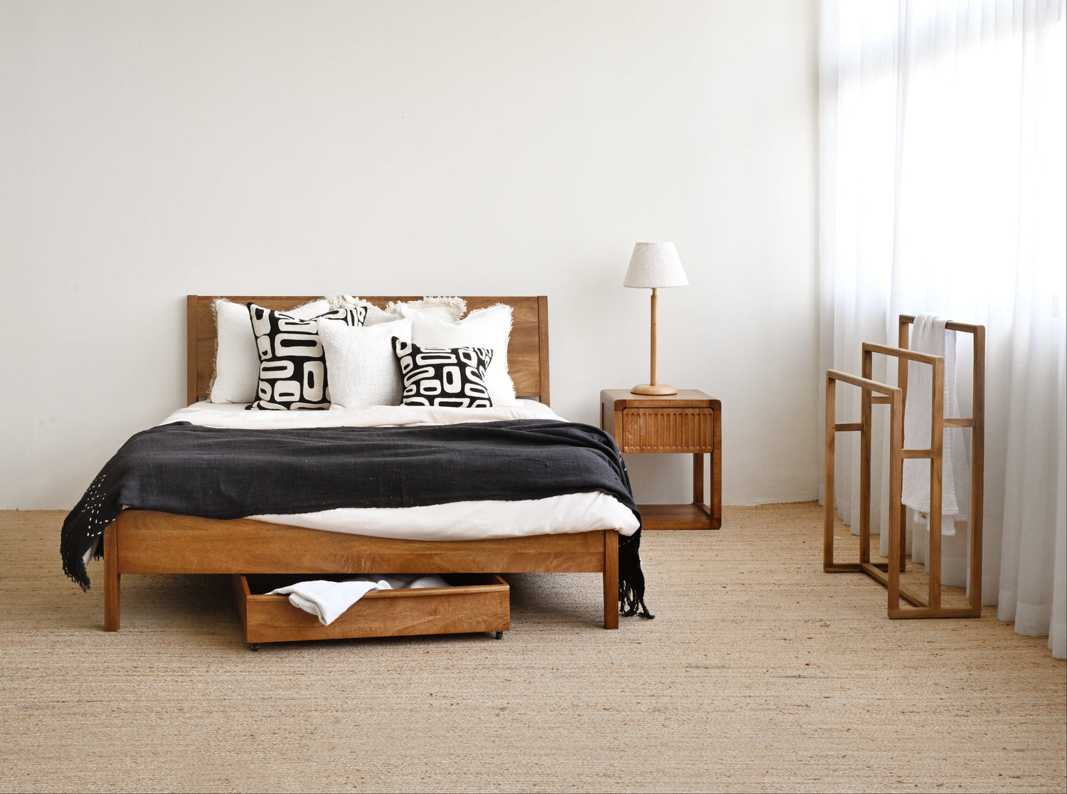 Wooden bed with storage drawers in a minimalistic bedroom setting.
