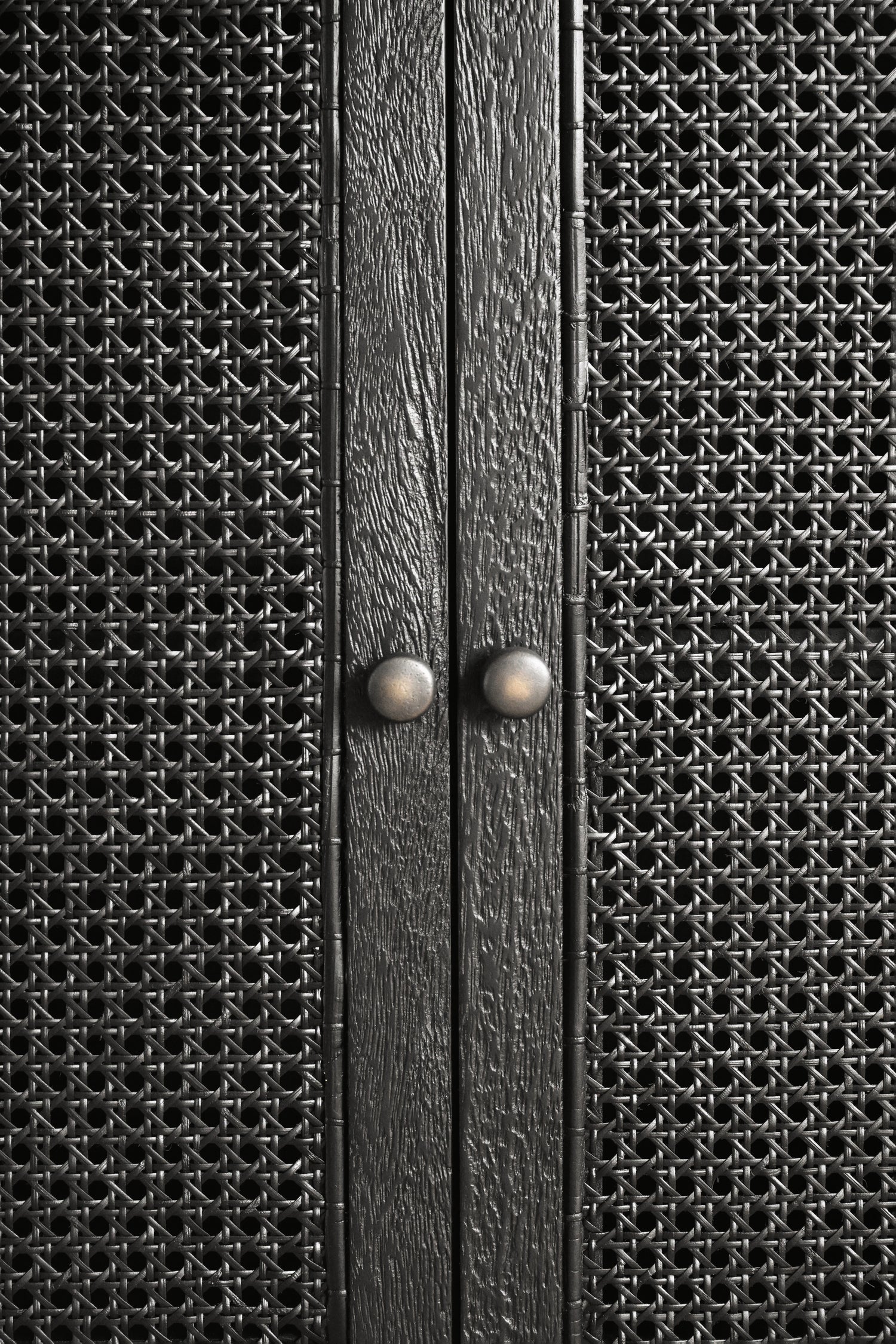 Close-up of a textured black cabinet with two knobs.