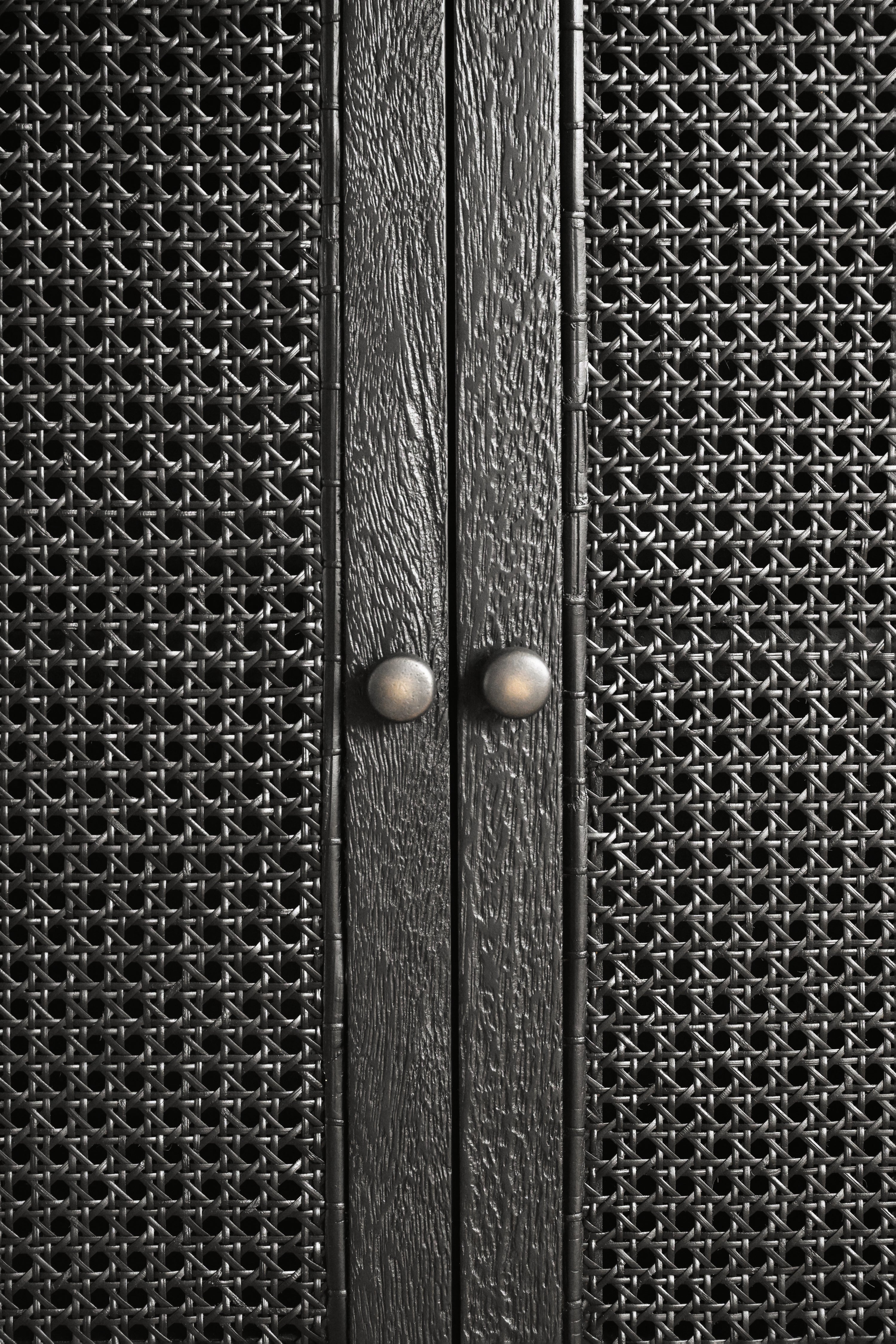 Close-up of a textured black cabinet with two knobs.