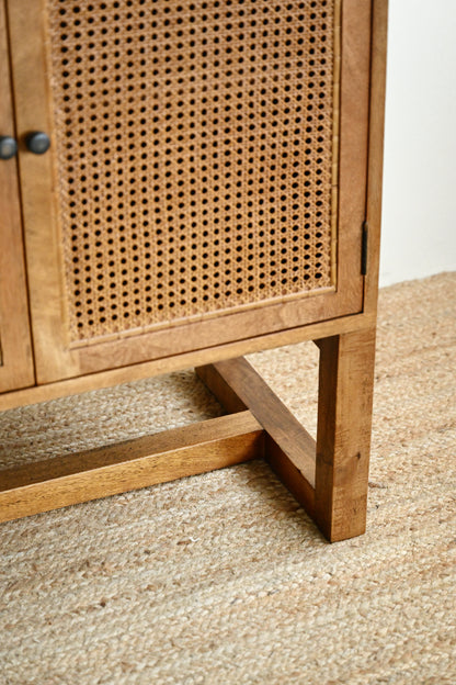 Wooden cabinet with wicker door on a textured floor