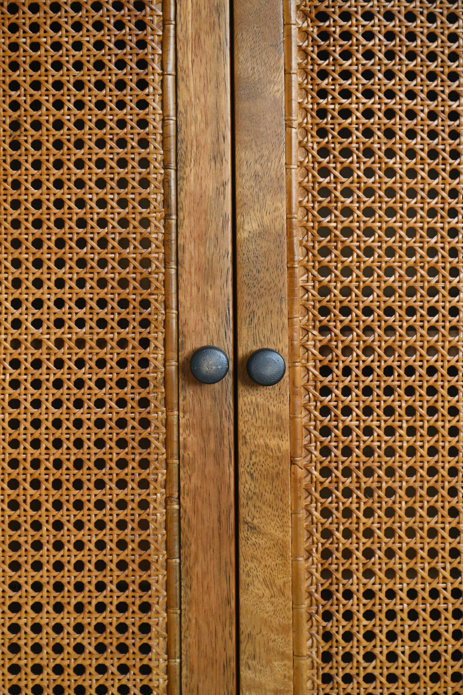 Close-up of a wooden cabinet with wicker doors and metal handles.