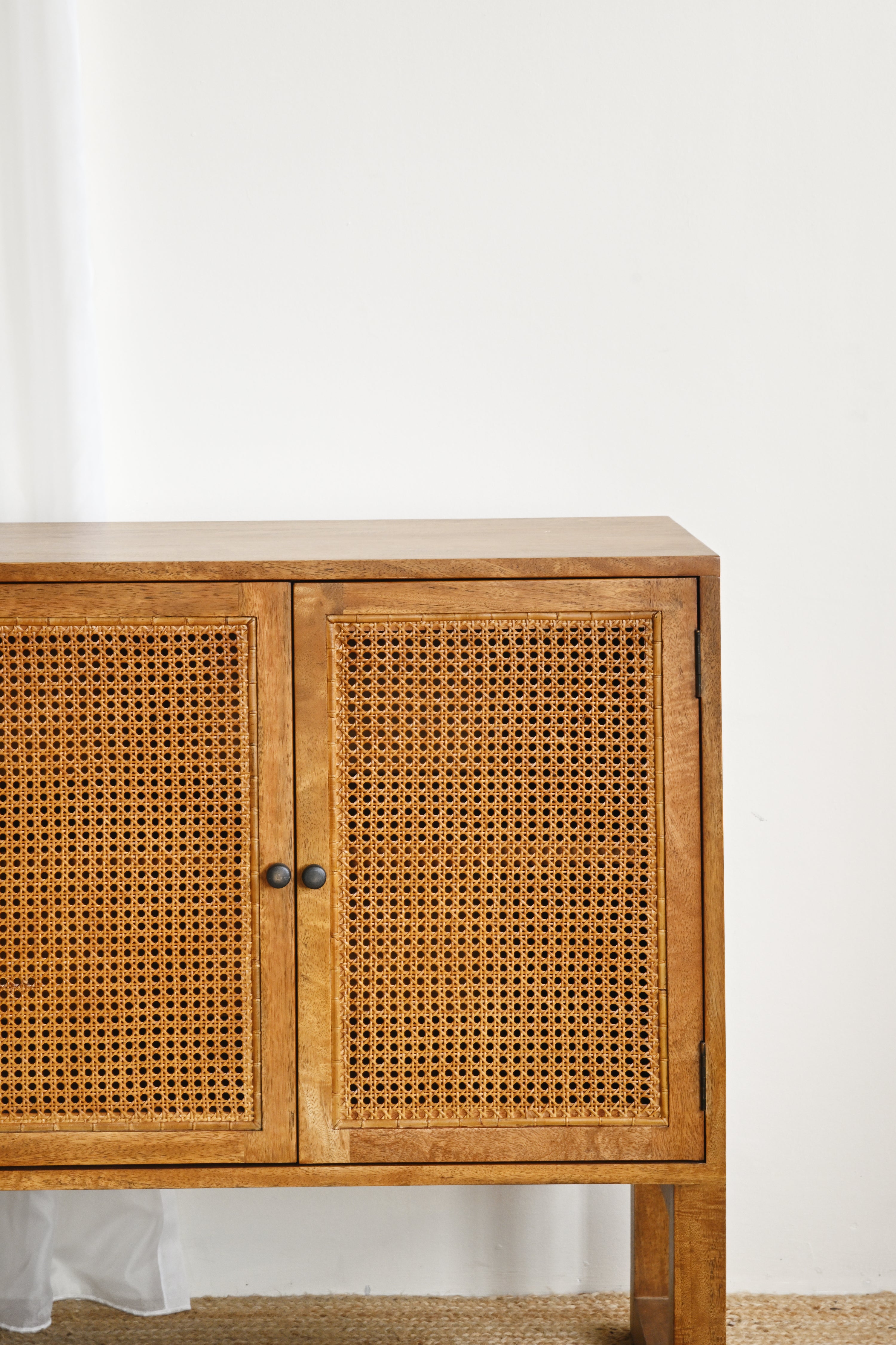 Wooden cabinet with wicker doors against a white wall