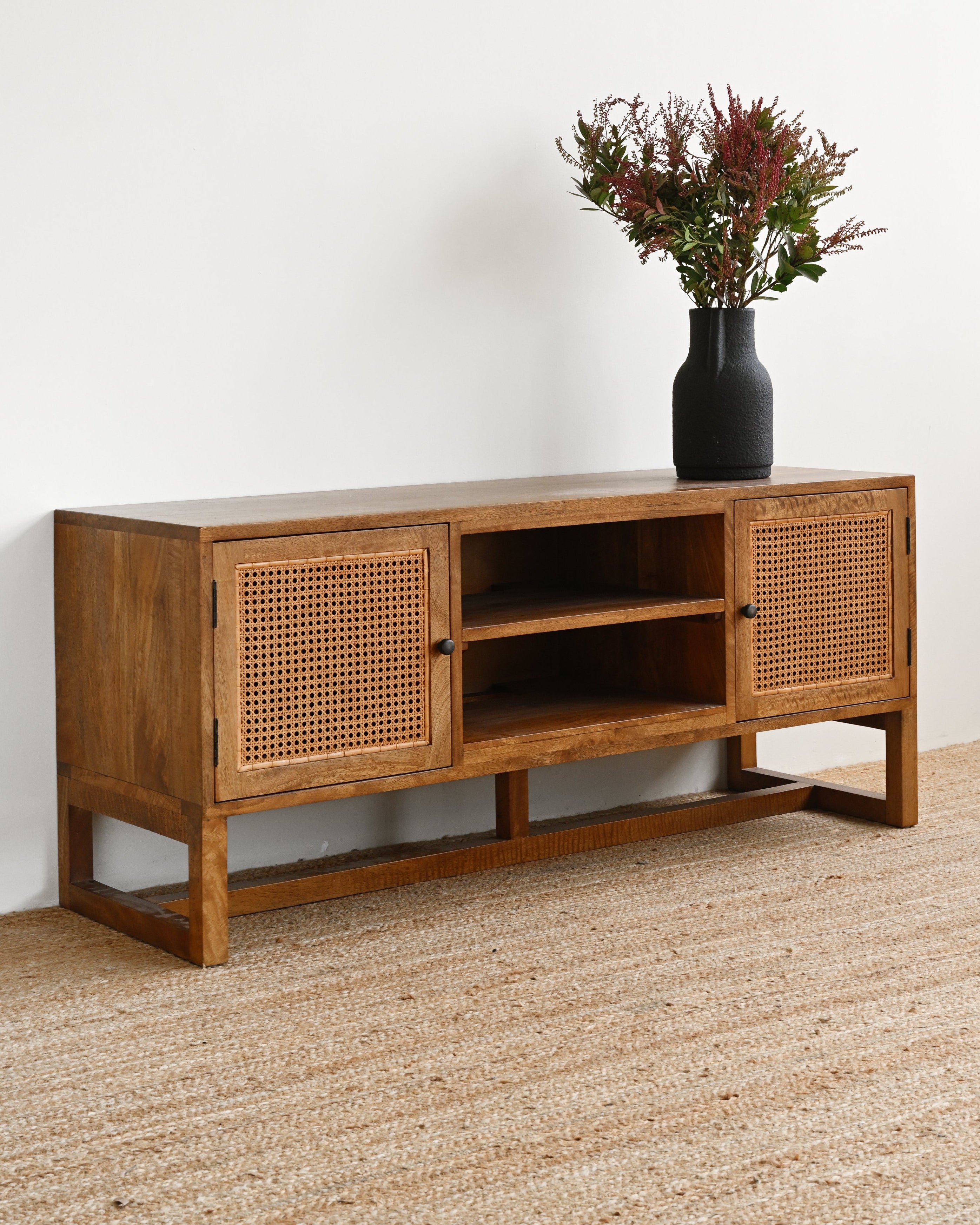 Wooden sideboard with wicker doors on a beige carpeted floor.