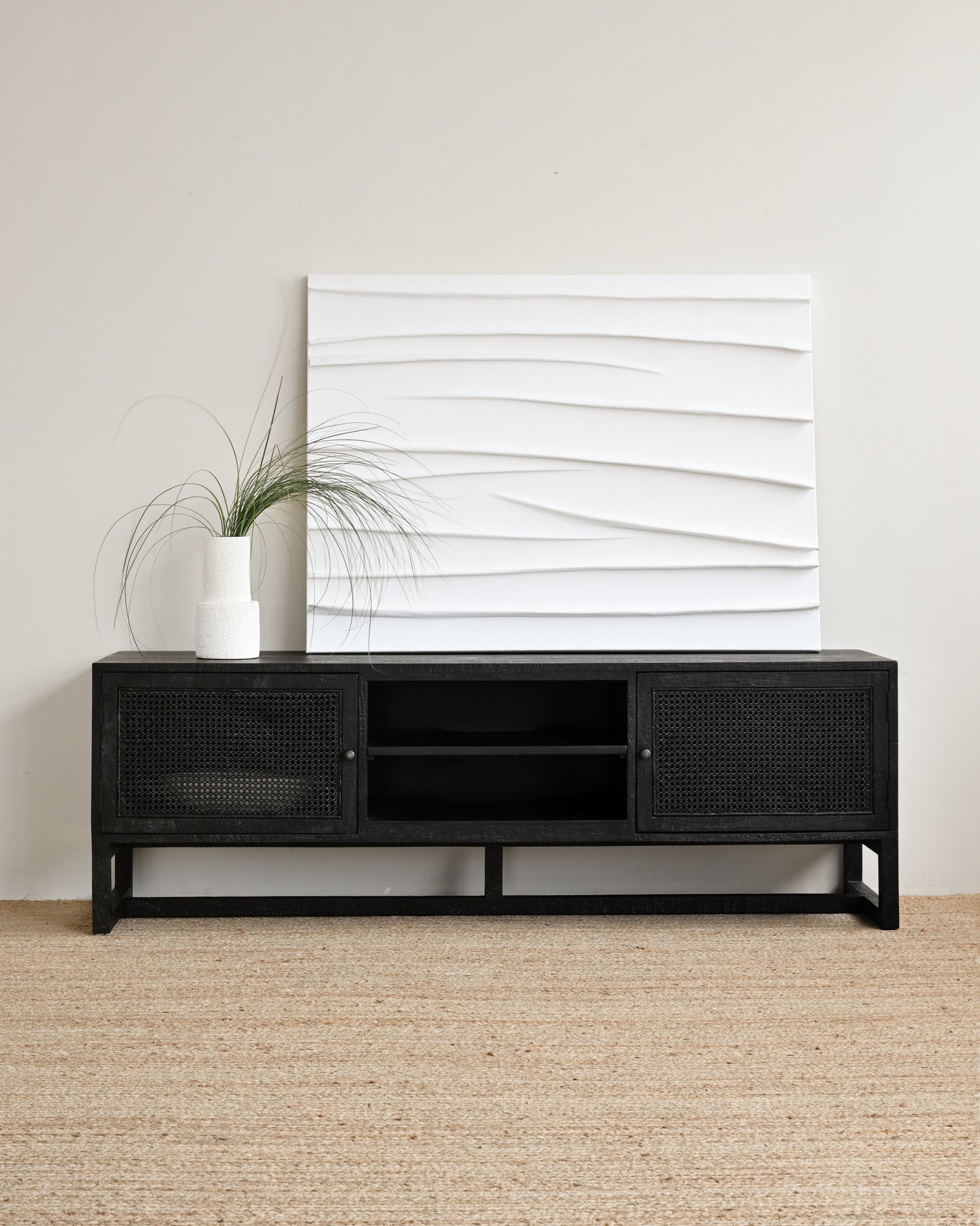 Black TV stand with a white abstract wall art piece in a minimalistic room.