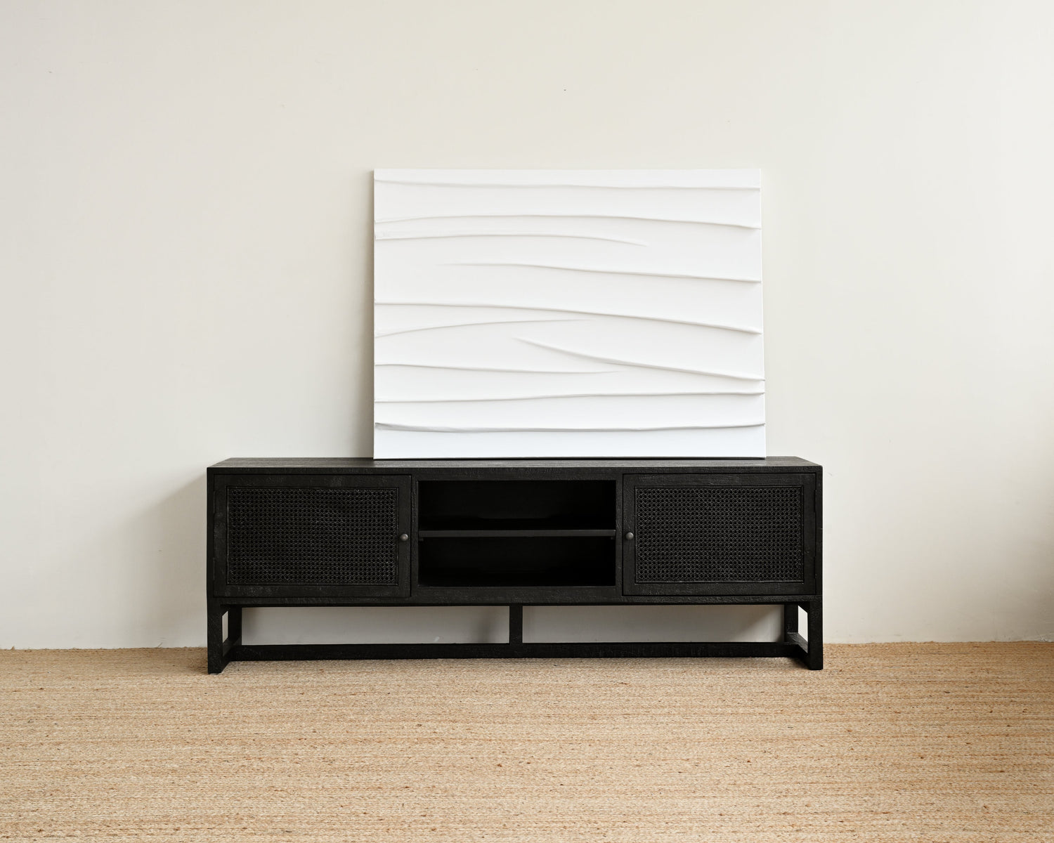 Black entertainment console with white abstract wall art against a beige wall.