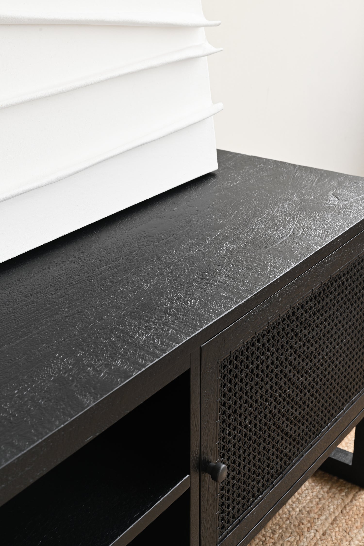 Black metal console table with a textured surface against a white wall.