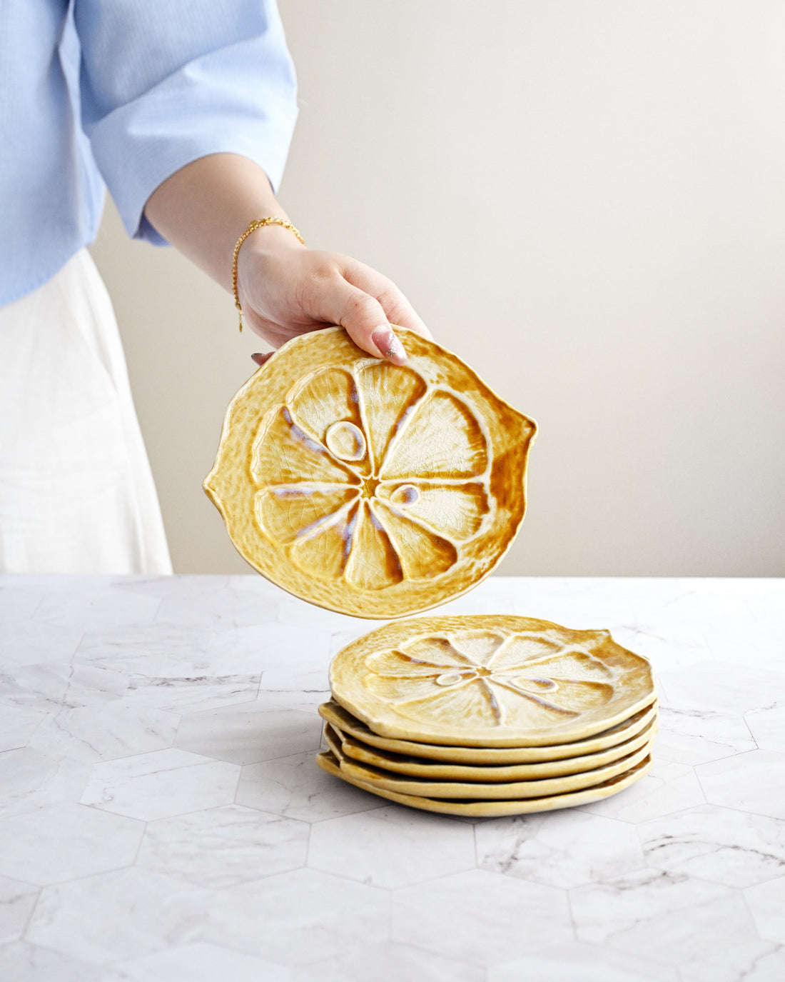 Person holding a stack of round, lemon-shaped cookies on a marble surface.