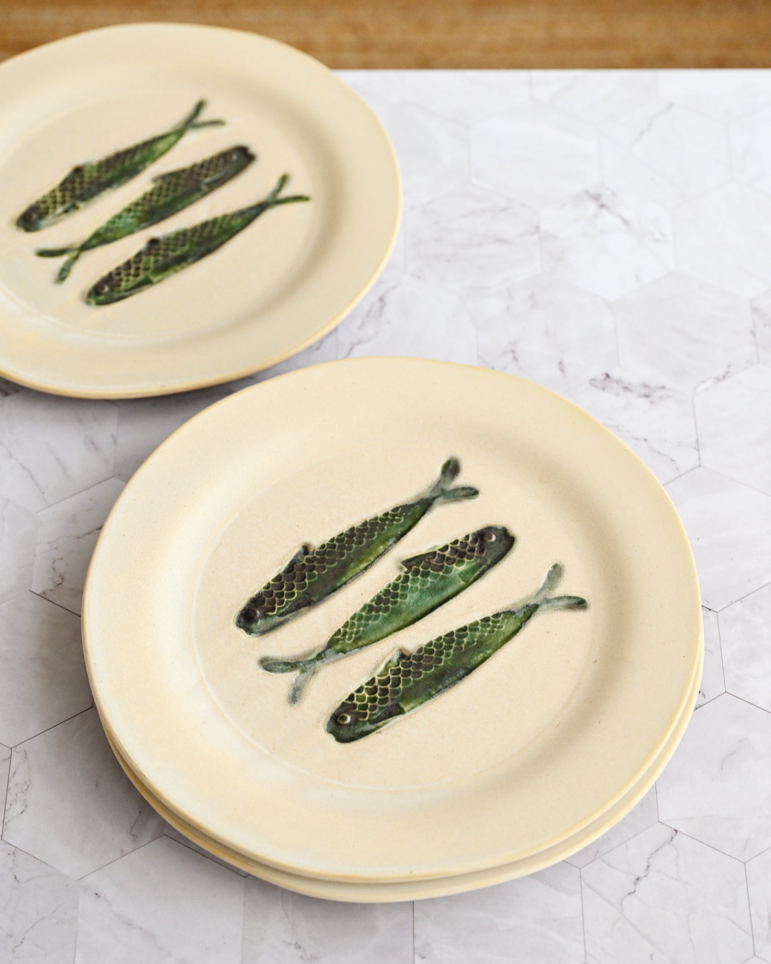 Two ceramic plates with fish-shaped decorations on a marble surface.