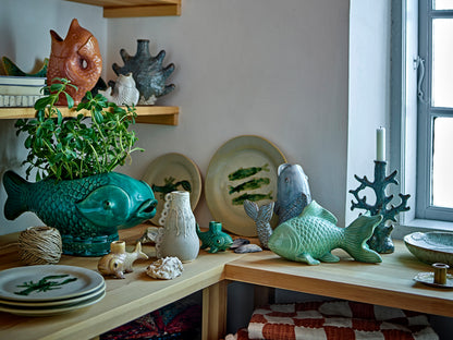 Decorative items including fish-shaped vases and ceramic figures on a wooden surface.