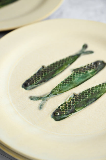 Three fish-shaped green cookies on a white plate