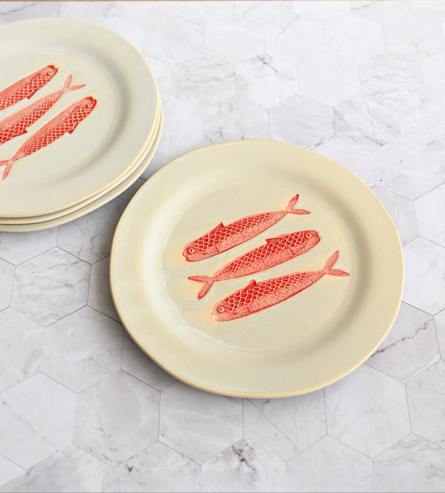 Set of plates with red fish design on a marble surface