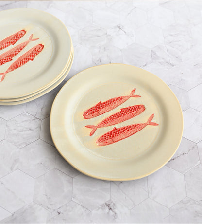 Set of plates with red fish design on a marble surface