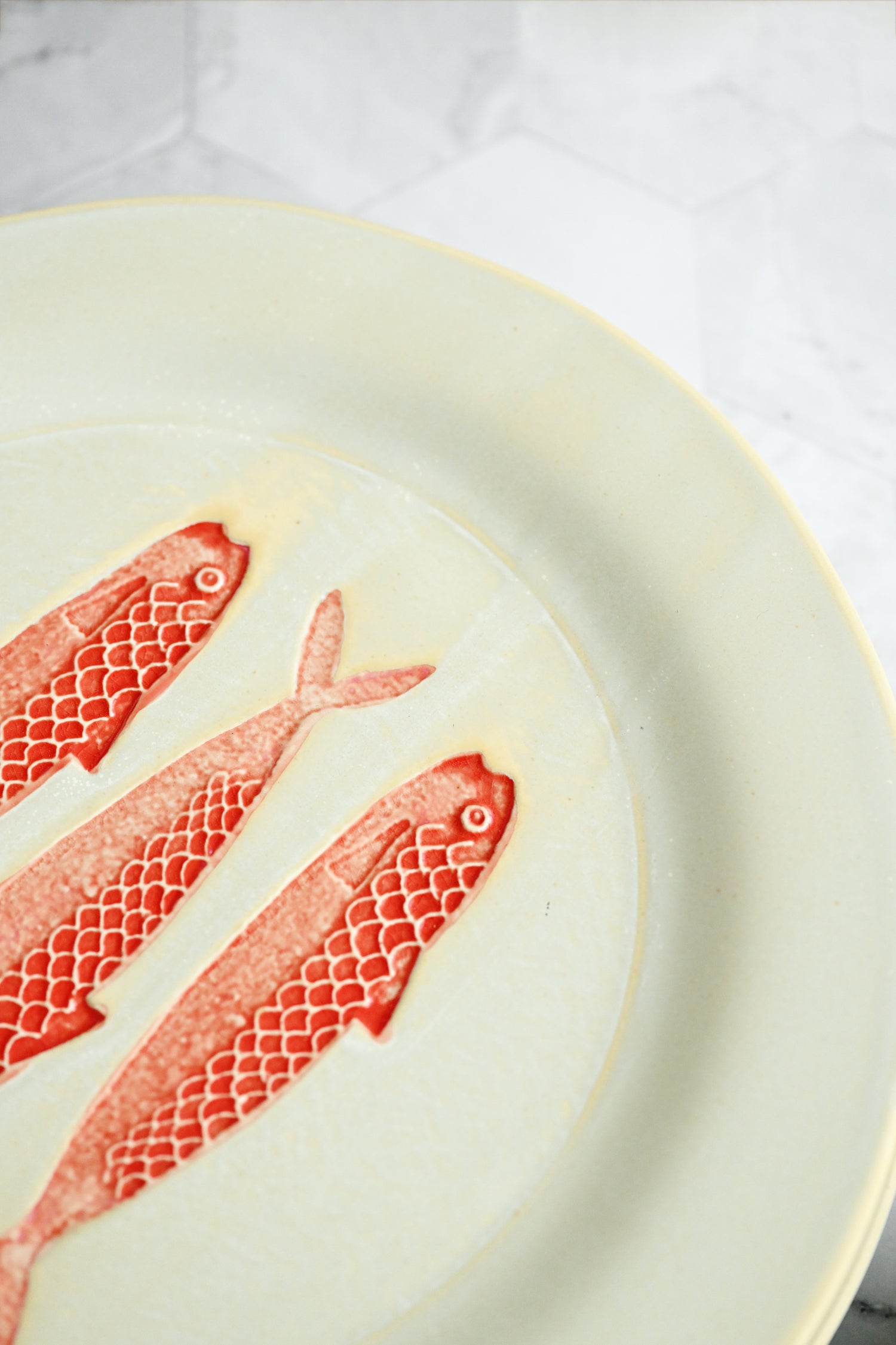 Three red fish-shaped cookies on a white plate with a white background