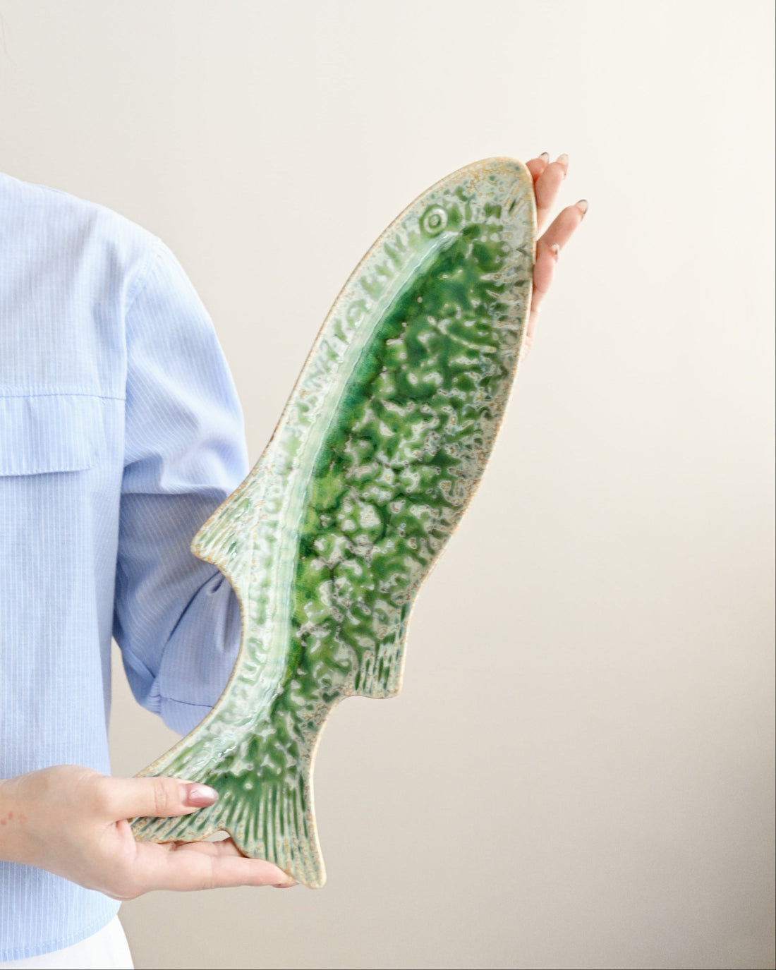 Person holding a large green and white shoe insert against a plain background