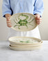 Person holding a ceramic plate with a crab design on a white background